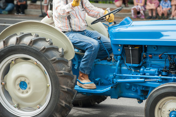 Vintage blue Ford tractor with big wheels and farmer.