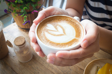 Woman holding hot cup of coffee, with heart shape