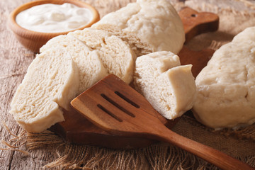 Fresh sliced yeast knedliks and sour cream close-up. horizontal
