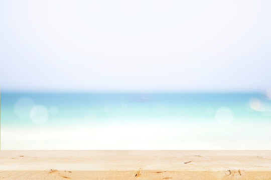Wooden table with defocused blue sea, white sand beach background.