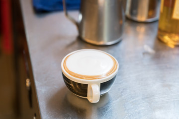 Barista creates a caramell picture in a cup of coffee latte
