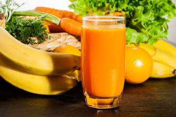 Glass of fruit juice with orange, carrots and banana