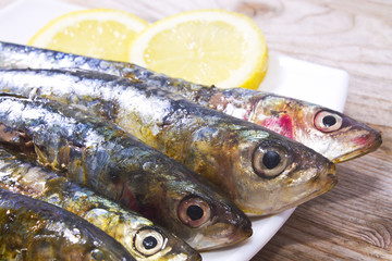 fish dish, grilled sardines with lemon on wooden background