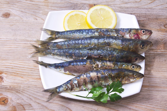 fish dish, grilled sardines with lemon on wooden background