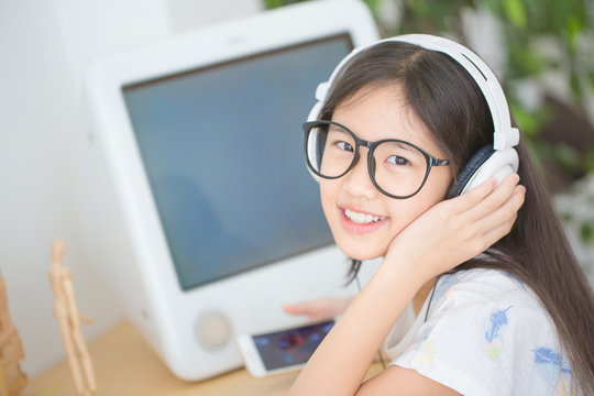 Happy Asian girl listening music on smartphone with headphone in the room