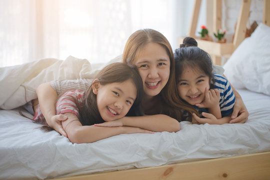 Healthy Asian family smiling and lying on the bed, Happy family
