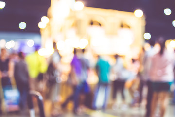 Blurred background: crowd of people in expo fair with bokeh ligh