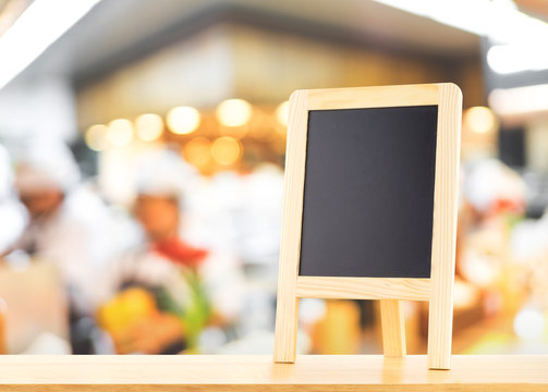 Blackboard with easel (menu board) on wooden table with blur bok
