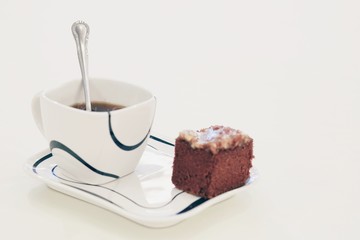 A cup of tea and brownie cake on white background.