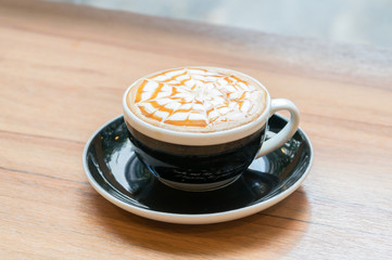 cup of caramel cappuccino coffee on wooden table
