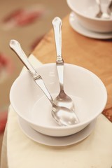 Empty white bowl with spoon on the table.