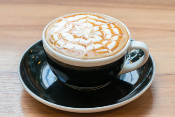 cup of caramel cappuccino coffee on wooden table
