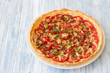 Delicious tomato tart with goat cheese, thyme and garlic on blue wooden table