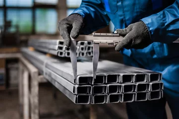 Deurstickers Factory worker measures the metal profile © flywish