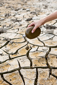 Man holding military flask on a background of a stone desert. Drought and climate change. Man searching for water.