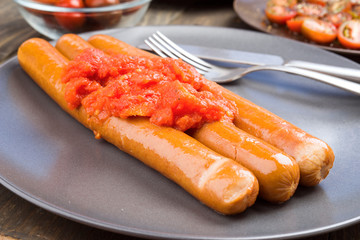Whole frankfurters, stewed with tomatoes in clay dish