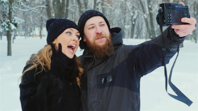 Young couple having fun in the forest - do selfie in snow