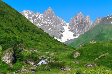 Fototapeta na wymiar Summer landscape with big stones and mountain snow.