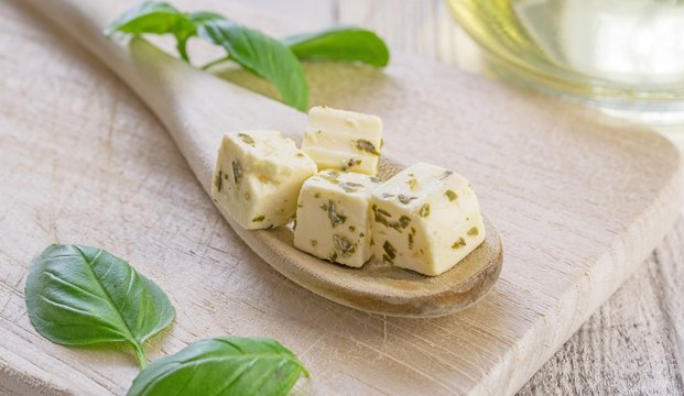 Traditional Greek feta cheese cubes on a wooden spoon
