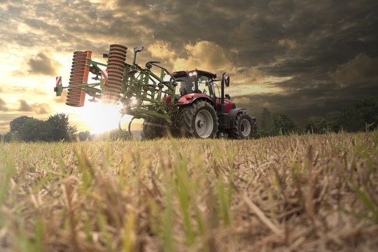 Traktor fähr auf dem Feld in den Sonnenuntergang
