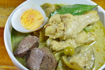 spicy chicken leg in green curry topping boiled egg on bowl