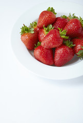 A bowl of fresh ripe strawberries on an off white background