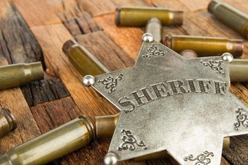 Sheriff badge and bullets shell on wooden background.  Stock image macro.