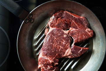 Steak cooking on grille pan. Fresh, delicious, spicy meat on a kitchen with copy space closeup
