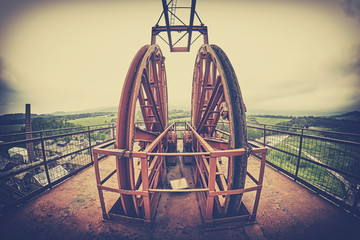 Vintage stylized fisheye lens photo of a mine shaft pulley wheel. Industrial detail background.
