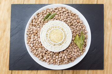 three kinds of uncooked rice and beans in porcelain bowls on a tray slate

