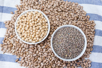 beans, chickpeas and lentils in porcelain bowls on a dishcloth
