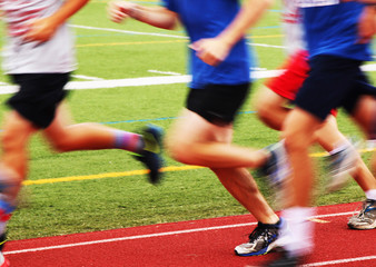 A group of blurred runners are running so fast on a track