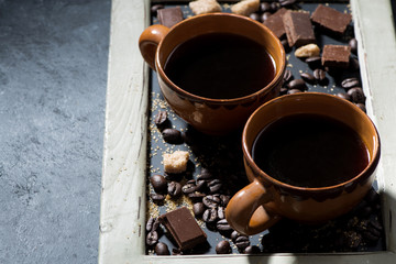 cups of black coffee, sugar and chocolate on a blackboard