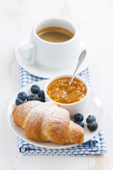 fresh croissant with orange jam, blueberries and coffee