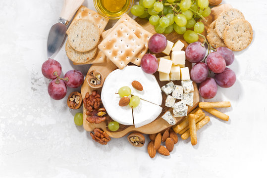 camembert, grapes and snacks on a white table