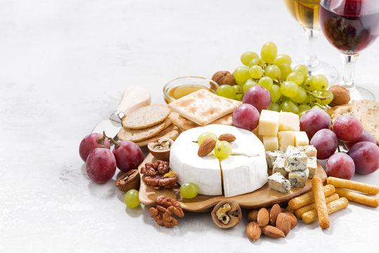 camembert, grapes, wine and snacks on a white table