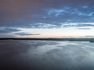 Sun setting over a lake in the woods, in summertime