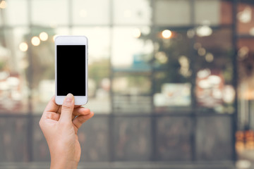 Smart phone with white screen in hand on blurred in shopping mall background,shopping online concept,shopping by smart phone