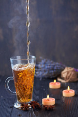 Pouring Healthy Tea with candles on a bakcground
