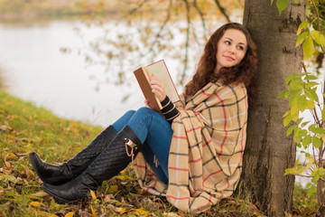 Naklejka premium Young woman with book in the park in the autumn