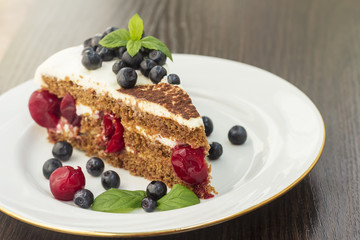 Piece of sweet cake with cherry, blueberry and mint