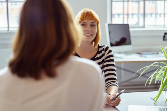 zwei frauen sitzen sich im b&uuml;ro gegen&uuml;ber in einer besprechung