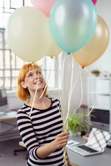 frau im büro freut sich über luftballons