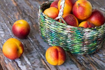  Ripe nectarines.    Ripe nectarines in a wicker basket on an old wooden table.