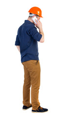 Backview of business man in construction helmet stands and enjoys tablet or using a mobile phone. Standing young guy. Rear view people collection.  backside view of person.  Isolated over white