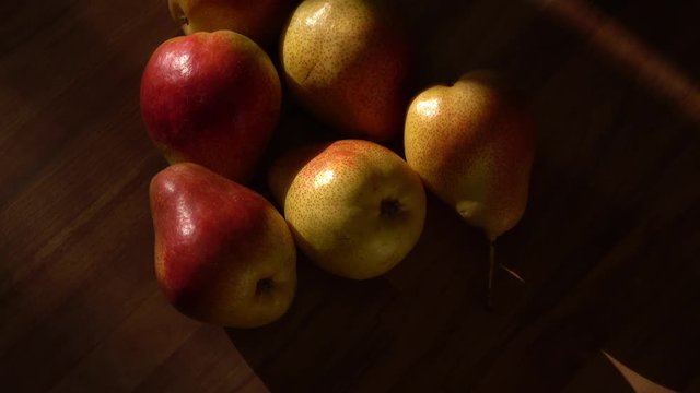 Ripe pears rotate on wooden background with natural sun light from the window. 4K UHD footage 3840x2160
