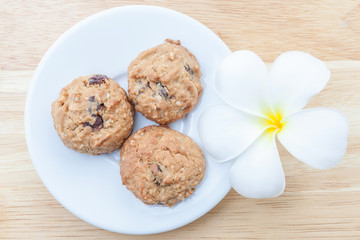 Tasty oatmeal cookies served on wooden board with flower decorat