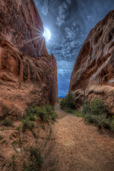 A narrow path through some Red Sandstone Rock, with the sun trying to burn through building storm clouds. © scottevers7