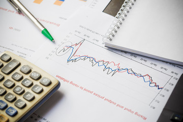 Papers with graphs data calculator and pen on wood table