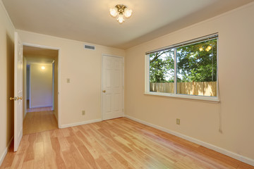 Empty room in warm peach colors with hardwood floor.